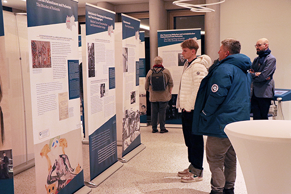 Menschen besuchen eine Ausstellung mit Stellwänden